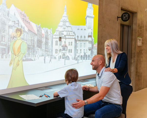 Familie in der Fabrik der F&auml;den an interaktiven Zeichenspiel